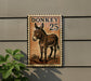 a donkey stamp with the number 25 on it, mounted on a wall next to a plant.