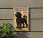a sign with a black dog illustration, mounted on a wall.