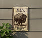 a sign with a picture of a buffalo, which is a symbol of the American bison, mounted on a wall.