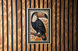 A framed illustration of a toucan bird is displayed on a wooden wall.