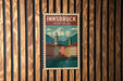 A vintage-style poster of Innsbruck, Austria, featuring a mountain landscape and colorful buildings, is displayed on a wooden wall.