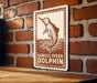 a sign with a dolphin illustration and the text "Ganges River Dolphin" on a brick wall.