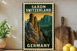 A vintage-style metal sign with a mountain landscape and text, mounted on a wall next to a wooden cutting board and some potted plants.