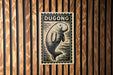 a wooden wall with a rectangular sign featuring a drawing of a dugout or dugout-like structure, along with the word "DUGONG" written on it.