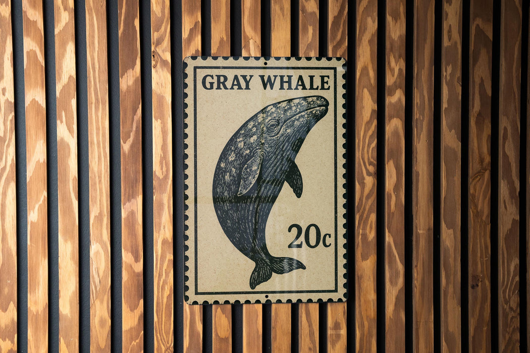 A postage stamp featuring a gray whale is displayed on a wooden wall.