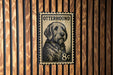 A metal stamp featuring a dog's head is displayed against a wooden background.