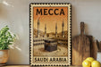 A framed poster of Mecca, the holy site in Saudi Arabia, is displayed on a shelf next to kitchen utensils and a potted plant.