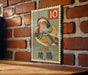 A vintage postage stamp featuring a colorful illustration of a bird, likely a duck, is displayed on a brick wall.