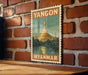 A vintage-style poster of the Shwedagon Pagoda, a famous Buddhist temple in Yangon, Myanmar, is displayed on a brick wall.