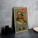 A metal stamp featuring a colorful illustration of a bird, likely a duck, with the number 10 on it, placed on a table next to some black camera lenses.