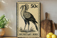 a decorative metal sign with a bird illustration, placed on a wooden surface next to a potted plant and a wooden cutting board.