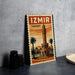 A vintage-style metal sign with the text "IZmir Turkey" and an illustration of a clock tower, palm trees, and a building, placed on a gray concrete surface.