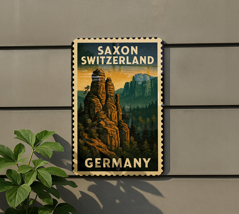 A vintage postage stamp depicting Saxon Switzerland, featuring a mountain landscape with trees and a castle, is displayed on a wall.