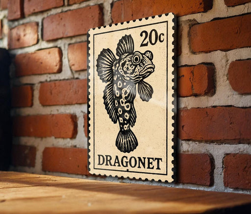 A 20c postage stamp featuring a dragon fish is displayed on a wooden surface against a brick wall.