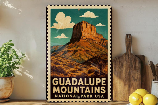 A vintage-style metal sign with a mountain landscape and clouds, featuring the text "GUADALUPE MOUNTAINS NATIONAL PARK USA".