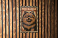 A metal sign featuring a pomeranian dog's portrait, mounted on a wooden wall.
