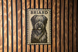 A metal sign with a black and white illustration of a dog's face, mounted on a wooden wall.