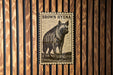 A brown hyena illustration on a wooden wall, with a black and white stamp-like design.