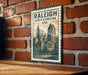 A metal sign with the text "RALEIGH NORTH CAROLINA USA" and an illustration of a city skyline, mounted on a brick wall.