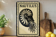 a decorative sign with a nautilus shell design, placed on a shelf next to a wooden cutting board and some lemons.