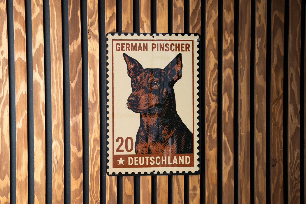 A German Pinscher dog is depicted on a German postage stamp, which is affixed to a wooden wall.