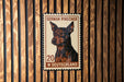 A German Pinscher dog is depicted on a German postage stamp, which is affixed to a wooden wall.