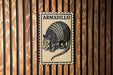 A metal sign with the word "ARMADILLO" printed on it, featuring an illustration of an armadillo.