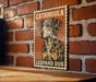 A framed poster of a leopard dog is displayed on a brick wall.