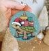 a hand holding a christmas ornament with a turtle on it