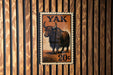 A yak stamp with the text "Yak" and "20¢" is displayed on a wooden wall.