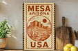 a vintage-style sign for MESA ARIZONA USA, with a desert landscape illustration and the text "MESA ARIZONA USA" prominently displayed.