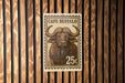 A metal sign with a picture of a buffalo and the text "CAPE BUFFO" is displayed on a wooden wall.