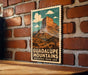A framed poster of the Grand Canyon, a famous landmark in the United States, is displayed on a brick wall.
