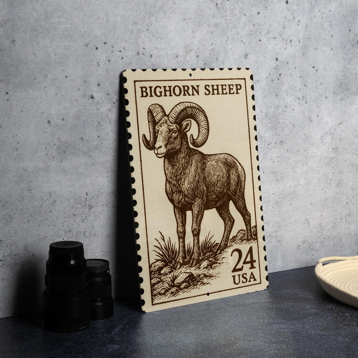 A large, brown, and white postage stamp featuring a detailed illustration of a bighorn sheep, with the text "BIGHORN SHEEP" and "24 USA" printed on it.