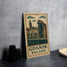 A vintage-style metal sign with a drawing of a cityscape and the text "Gdansk Poland" on it, placed on a gray countertop next to some black camera lenses.