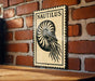 A metal sign with a nautilus shell design is mounted on a brick wall.