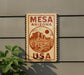 A sign for Mesquite, Arizona, USA, featuring a desert landscape with mountains and cacti.