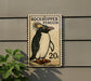 A postage stamp featuring a penguin is displayed on a wall, with a plant visible to the left.