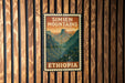 A vintage-style metal sign with the text "SIMIEN MOUNTAINS" and "ETHIOPIA" displayed on a wooden wall.