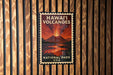 A vintage-style stamp depicting a volcanic eruption in Hawaii, with the text "HAWAII VOLCANOES" and "NATIONAL PARK USA" printed on it.