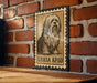 A framed illustration of a long-haired dog, likely a breed like a Shih Tzu or similar, is displayed on a brick wall.