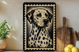 a framed black and white illustration of a Dalmatian dog, which is the central focus of the image. The framed picture is placed on a wooden surface, surrounded by various kitchen items such as a cutting board, a knife, and a bowl.