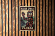 A metal sign with a stylized illustration of a bear and the text "HAIDA GWALL CANADA" is displayed on a wooden wall.