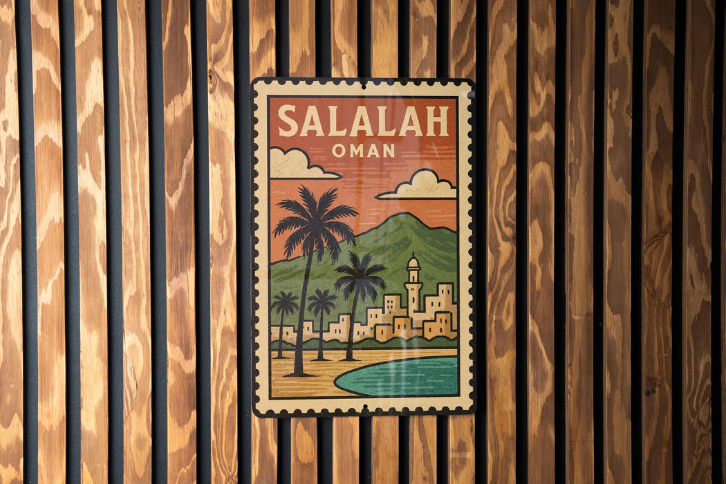 A vintage-style poster of Salalah, Oman, featuring a palm tree and a cityscape, is displayed on a wooden wall.