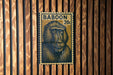 A postage stamp featuring a monkey's face is displayed on a wooden wall.