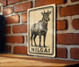 a sign with a black and white illustration of a cow, mounted on a brick wall.