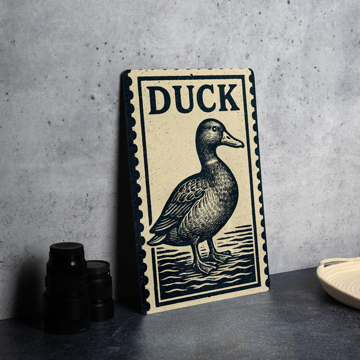a wooden sign with a duck illustration, placed on a table next to some black camera lenses.