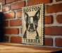 A vintage-style metal sign featuring a black and white illustration of a Boston Terrier dog, mounted on a brick wall.