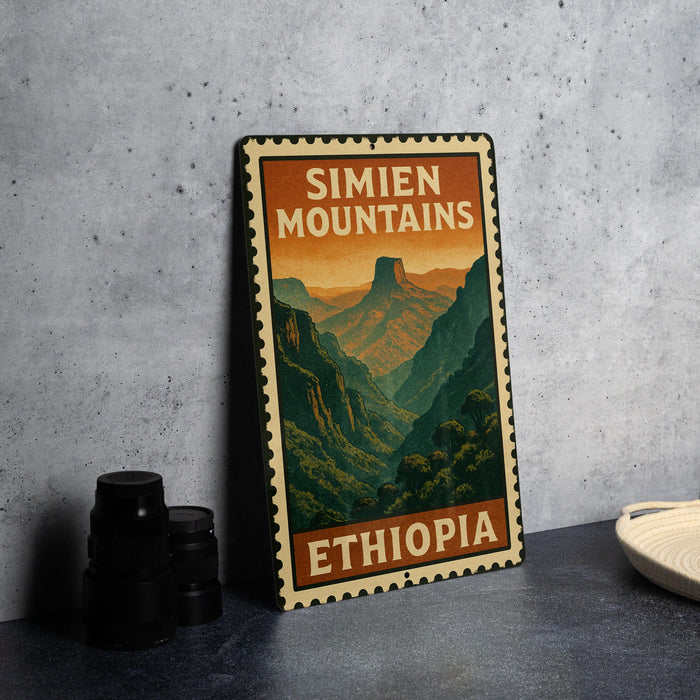 A vintage-style metal sign with the text "SIMIEN MOUNTAINS ETHIOPIA" printed on it, depicting a mountainous landscape. The sign is placed on a gray countertop next to some black camera lenses.