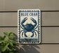 a sign with a blue crab illustration on it, mounted on a wall.